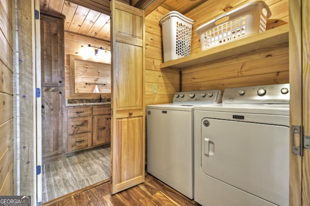 washroom with washer and dryer, laundry area, wooden walls, and wood finished floors