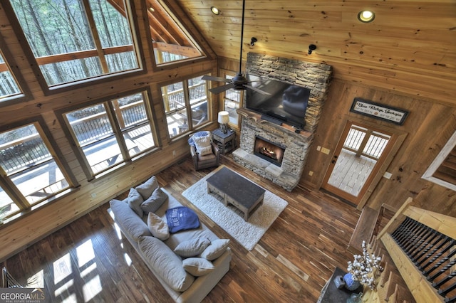 living room with wood walls, a fireplace, hardwood / wood-style flooring, plenty of natural light, and high vaulted ceiling