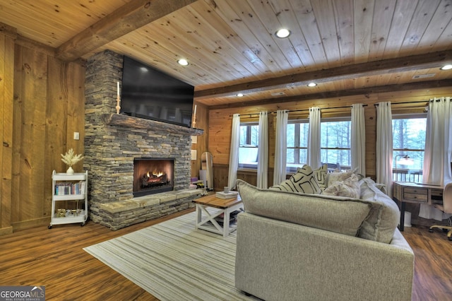 living area featuring wood finished floors, a stone fireplace, wood walls, wooden ceiling, and beamed ceiling