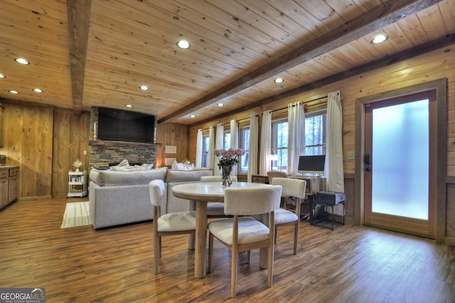 dining space with beamed ceiling, wood walls, recessed lighting, wooden ceiling, and wood finished floors