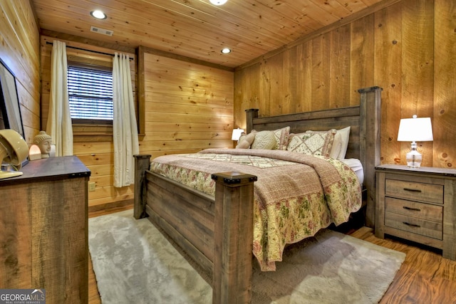 bedroom featuring visible vents, wood walls, wood ceiling, and wood finished floors