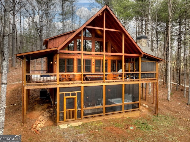 back of house with central AC, a chimney, a sunroom, and a wooden deck