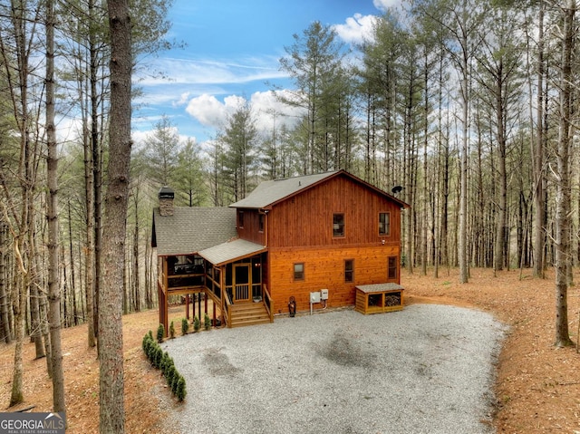 view of front of home featuring a chimney, gravel driveway, and a shingled roof