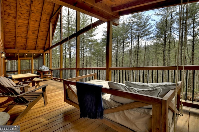 sunroom / solarium featuring wood ceiling, vaulted ceiling with beams, and a view of trees