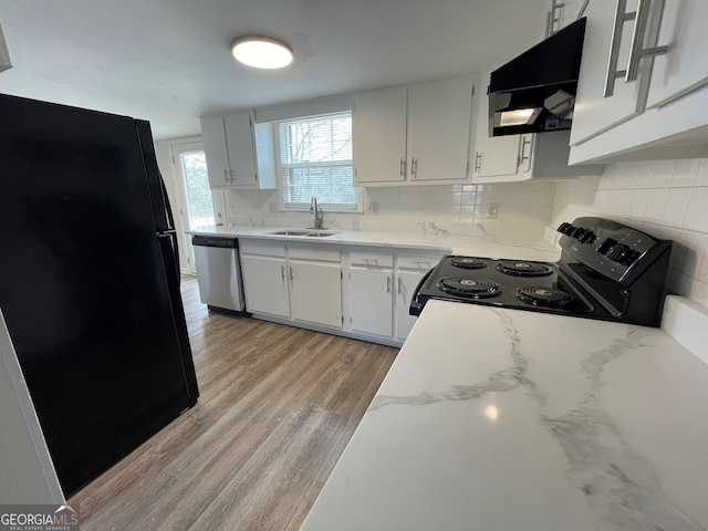 kitchen with light wood-type flooring, decorative backsplash, range hood, black appliances, and a sink