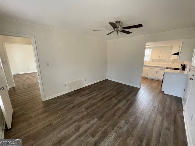 unfurnished living room featuring crown molding, visible vents, dark wood-style flooring, and ceiling fan