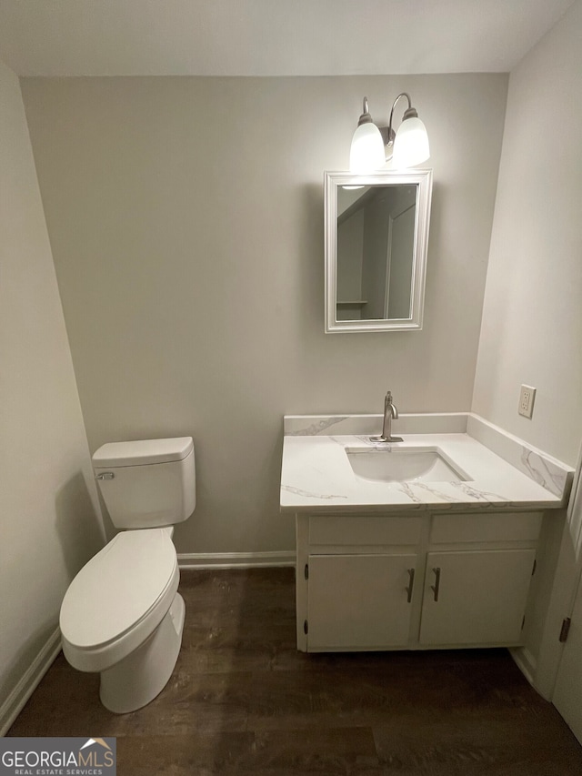 bathroom with baseboards, toilet, wood finished floors, and vanity