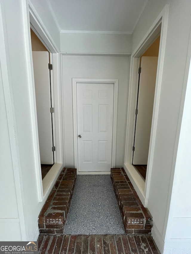 interior space with crown molding and brick floor