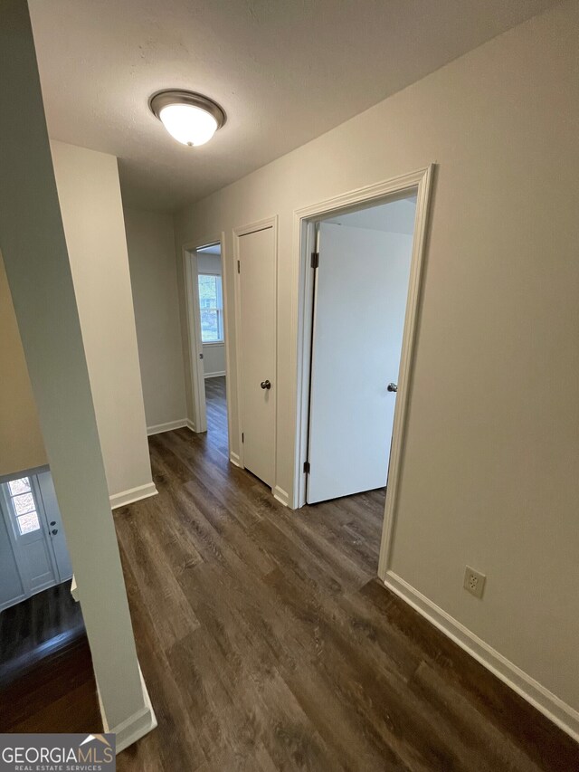 hallway with dark wood-style floors and baseboards