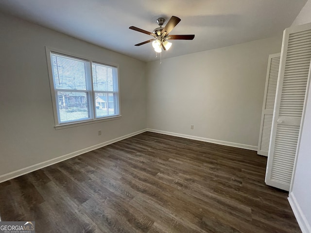 unfurnished bedroom with dark wood-type flooring, a ceiling fan, and baseboards