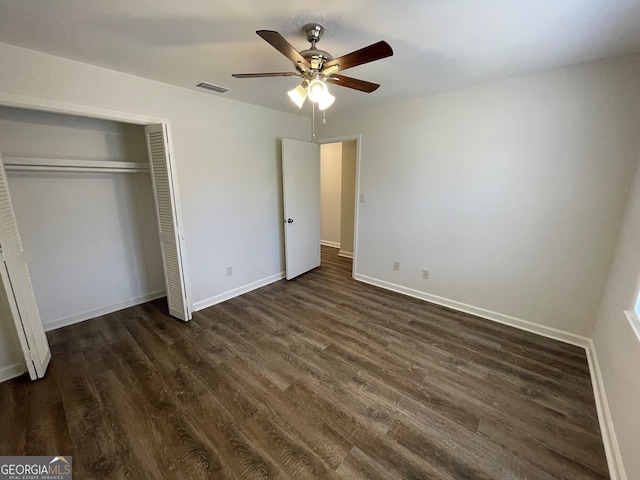 unfurnished bedroom with a ceiling fan, baseboards, visible vents, dark wood-type flooring, and a closet