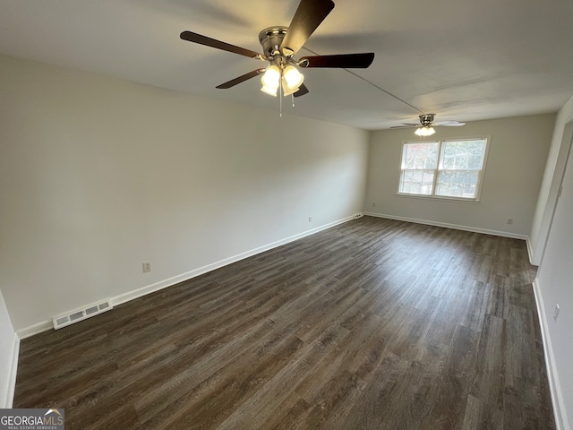 empty room featuring dark wood finished floors, visible vents, and baseboards