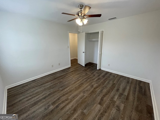 unfurnished bedroom featuring visible vents, dark wood-type flooring, ceiling fan, baseboards, and a closet