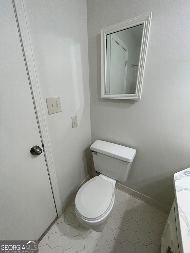 bathroom featuring baseboards, toilet, vanity, and tile patterned flooring