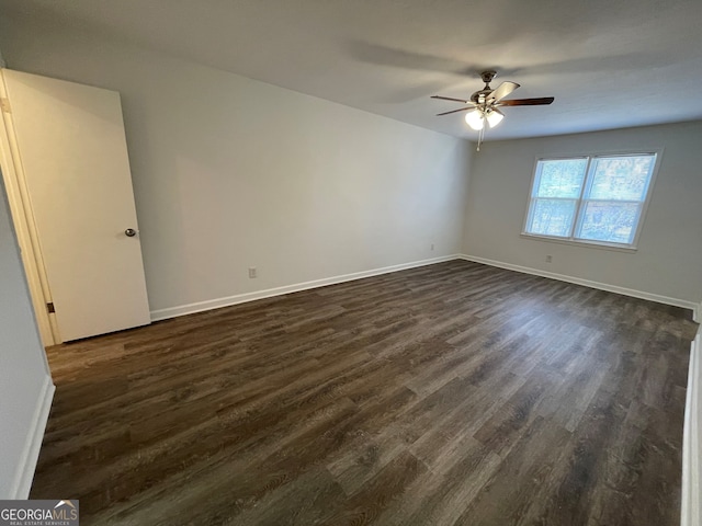 unfurnished room featuring dark wood-type flooring, a ceiling fan, and baseboards