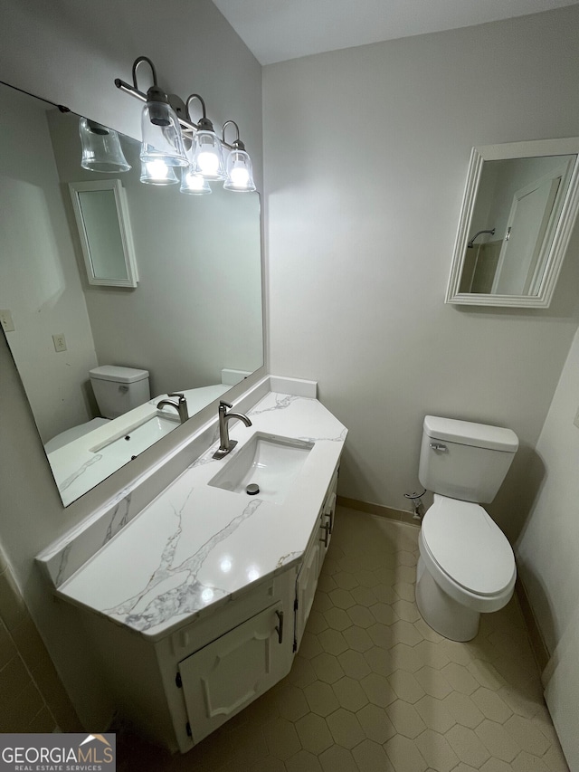 bathroom with toilet, vanity, and baseboards