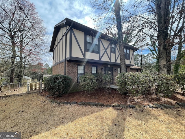 view of side of home with stucco siding, brick siding, and fence