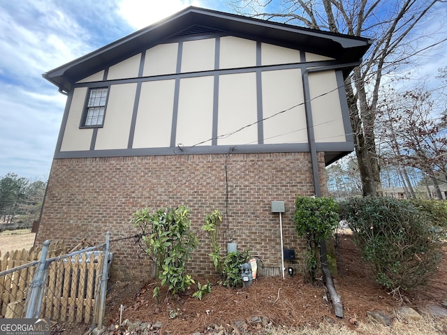 view of property exterior featuring fence, brick siding, and stucco siding