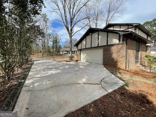 view of side of home featuring a garage, brick siding, and driveway