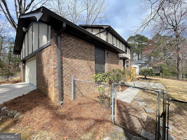 view of home's exterior featuring a gate, brick siding, driveway, and fence