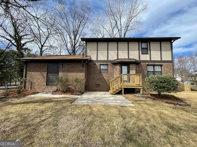 rear view of property with crawl space, brick siding, a yard, and fence