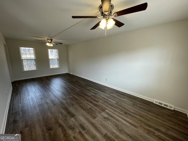 spare room with visible vents, baseboards, and dark wood finished floors