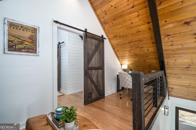 office space featuring vaulted ceiling, wood ceiling, a barn door, and wood finished floors