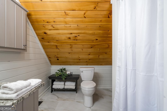 full bath with wooden walls, marble finish floor, toilet, and a shower with curtain