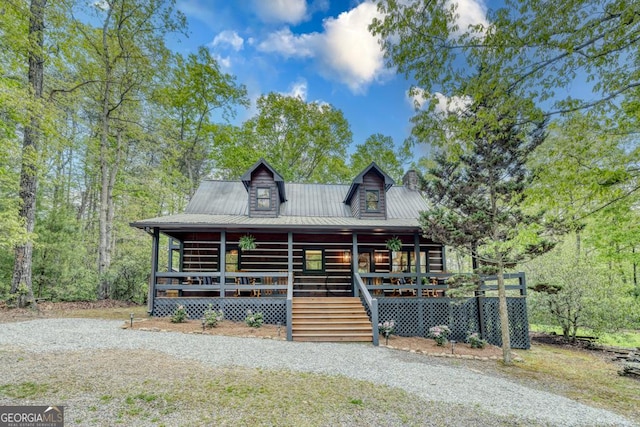 log-style house featuring metal roof, a porch, and a chimney