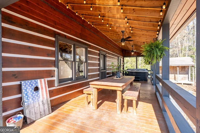 wooden terrace featuring ceiling fan, outdoor dining space, and a hot tub