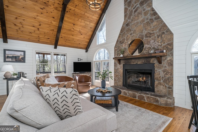 living area with a stone fireplace, beamed ceiling, wood ceiling, and hardwood / wood-style floors