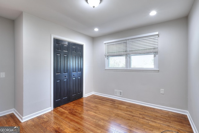 unfurnished bedroom featuring wood finished floors, visible vents, baseboards, recessed lighting, and a closet