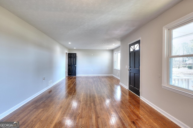 foyer featuring visible vents, a textured ceiling, baseboards, and hardwood / wood-style flooring