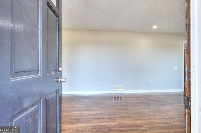 unfurnished room featuring recessed lighting, wood finished floors, visible vents, and baseboards