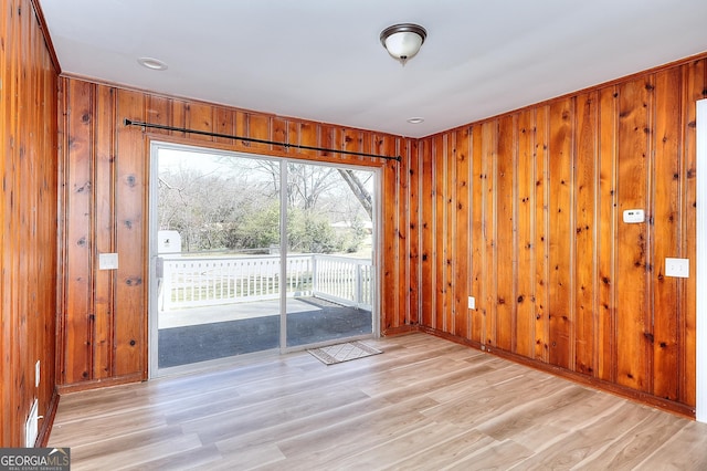 spare room with light wood-style floors and wood walls