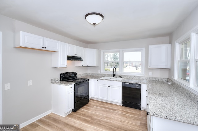 kitchen featuring under cabinet range hood, light stone countertops, black appliances, and a sink