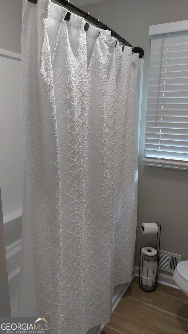 bathroom featuring visible vents, toilet, curtained shower, wood finished floors, and baseboards