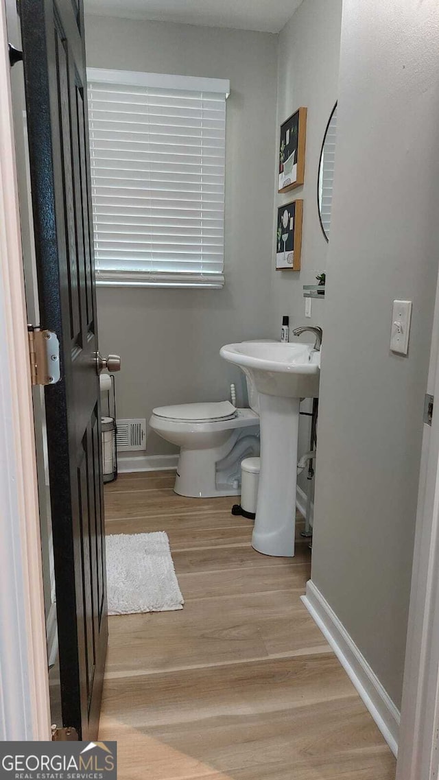 half bathroom featuring visible vents, toilet, baseboards, and wood finished floors