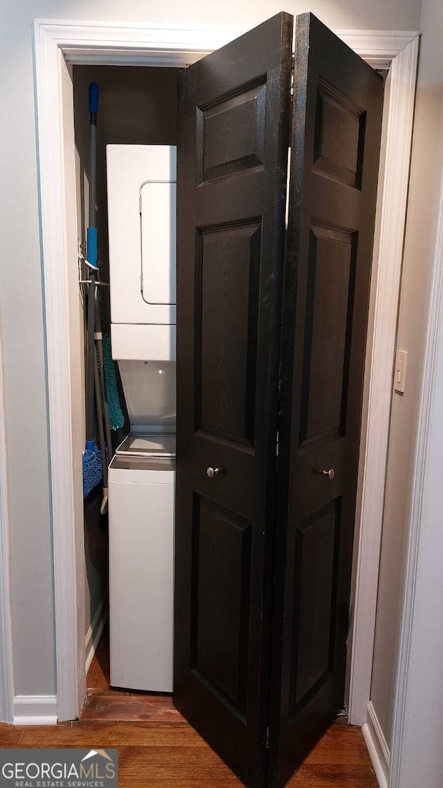 laundry room with stacked washer / dryer, laundry area, and wood finished floors