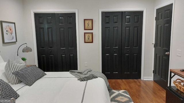 bedroom with wood finished floors and two closets