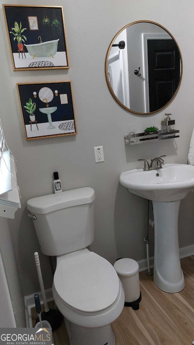 half bathroom featuring baseboards, toilet, and wood finished floors