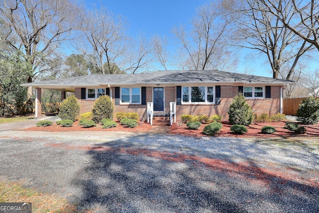 single story home featuring an attached carport, fence, brick siding, and driveway