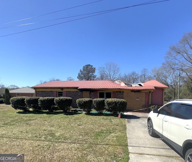 view of front of home featuring metal roof, brick siding, concrete driveway, and a front lawn