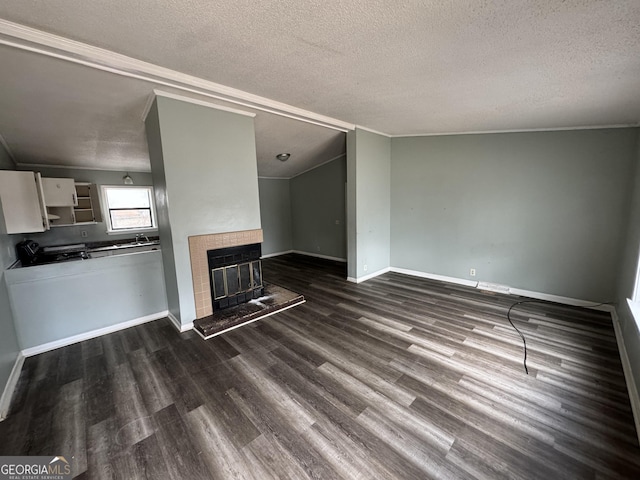 unfurnished living room featuring dark wood finished floors, a textured ceiling, baseboards, and a tile fireplace