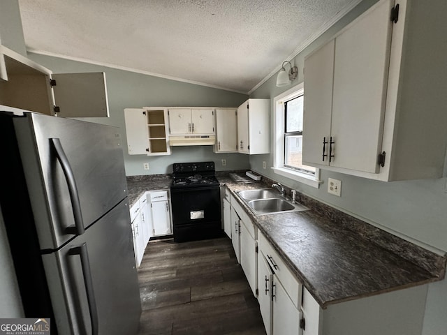 kitchen featuring freestanding refrigerator, a sink, under cabinet range hood, black range with gas stovetop, and dark countertops