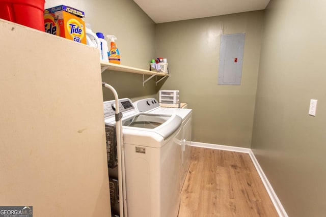 washroom featuring washer and clothes dryer, electric panel, light wood finished floors, baseboards, and laundry area