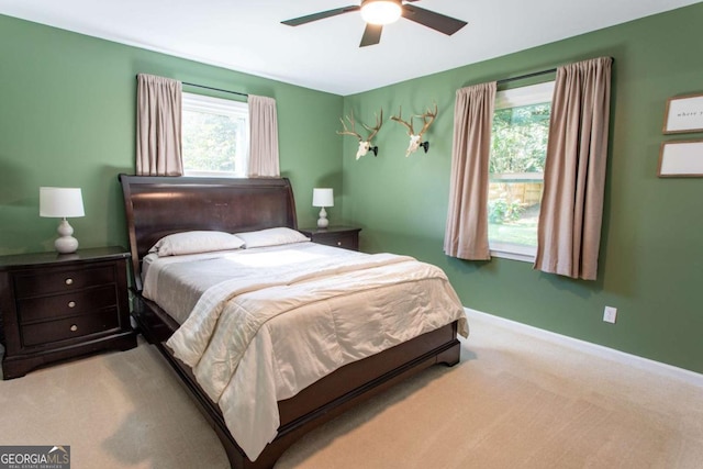 carpeted bedroom featuring multiple windows, baseboards, and ceiling fan