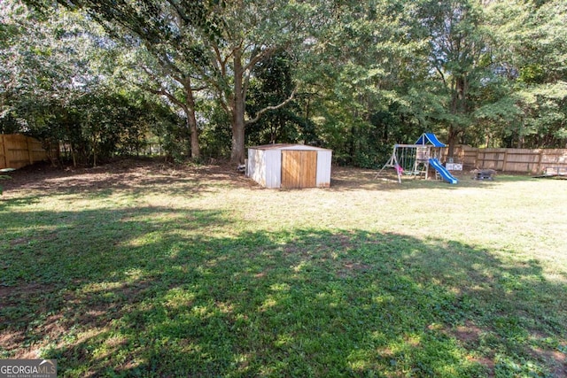 view of yard with an outdoor structure, a playground, a storage unit, and a fenced backyard