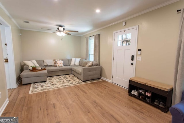 living room with ornamental molding, baseboards, visible vents, and light wood-type flooring