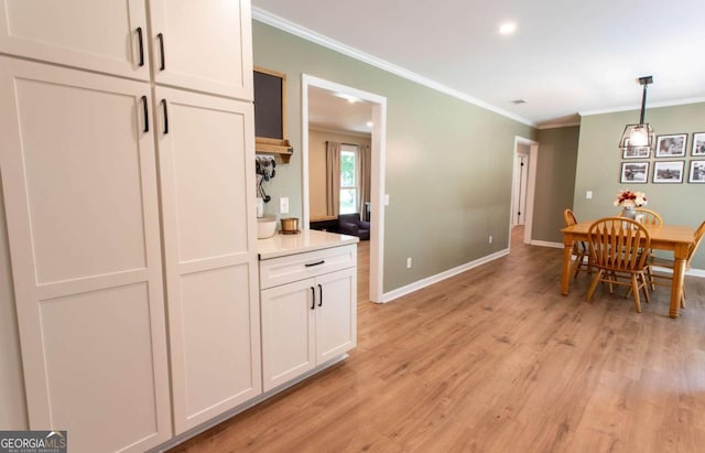 dining room with light wood-style flooring, baseboards, and ornamental molding